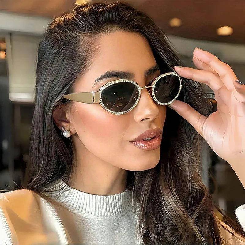 Óculos de sol femininos ovais dourados com lentes escuras e detalhe brilhante