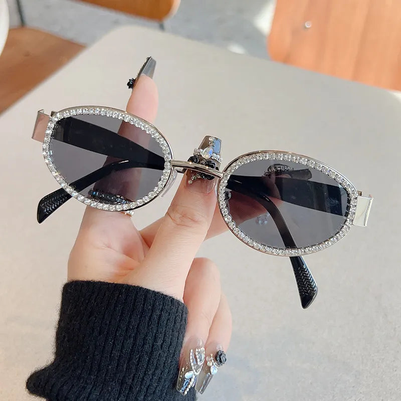 Óculos de sol ovais prateados com lentes escuras e detalhe brilhante